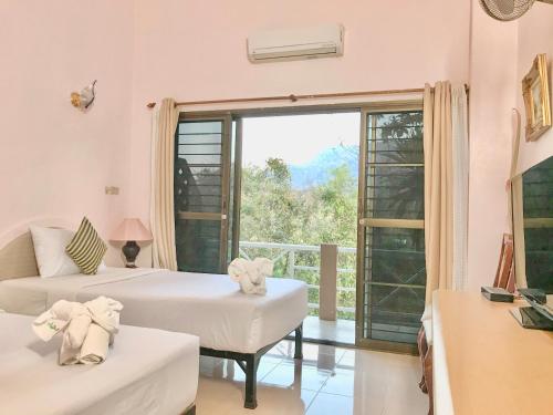 a room with two beds and a large window at Phurua Bussaba Resort & Spa in Loei