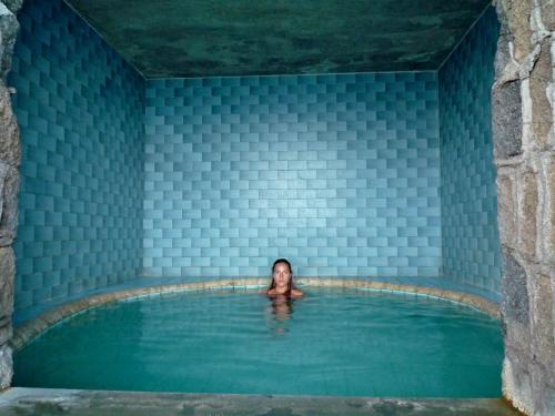 a woman in a bath tub in a room with blue tiles at Hotel La Gondola in Ischia