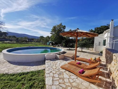 uma piscina com duas cadeiras e um guarda-sol em Hvar Mediterranean Ranch House em Stari Grad