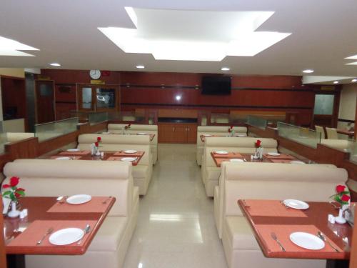 a dining room with tables and chairs and a television at Kediyoor Hotels in Udupi
