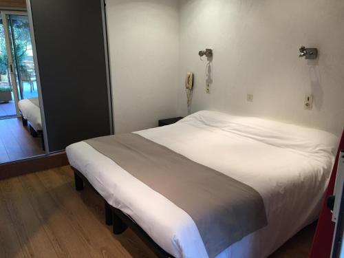 a bed in a room with a phone on the wall at Hôtel Beau Soleil in Le Lavandou