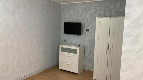 Habitación con armario blanco y TV en la pared. en Casa The Grey House Caciulata/Calimanesti, en Căciulata