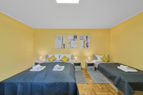 two beds in a room with yellow walls at DuMalux Garden in Subotica