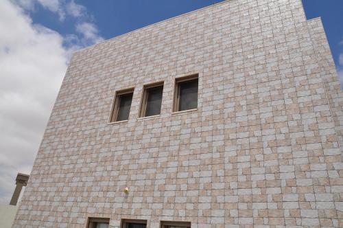 a tall brick building with three windows on it at Vastu Dead Sea apartment in Arad
