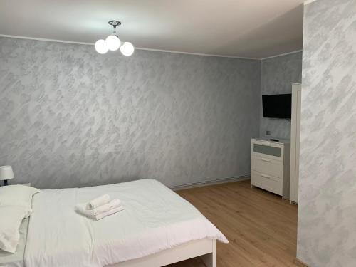 1 dormitorio con 1 cama blanca y TV en Casa The Grey House Caciulata/Calimanesti, en Căciulata