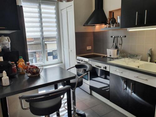 une cuisine avec des placards noirs et un comptoir avec deux tabourets dans l'établissement GRAND T3 70m2 ,COSY TOUT CONFORT ,2 CHAMBRES, à Reims