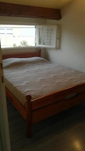 - un lit en bois dans une chambre avec fenêtre dans l'établissement SUN, à Portiragnes
