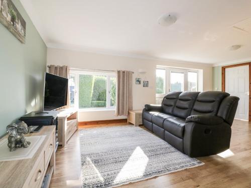 a living room with a black leather chair and a television at Lower Brambleside in Truro