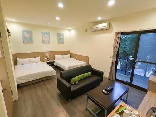 澎湖夏日南風民宿 في ماغونغ: غرفة معيشة بها سريرين وأريكة