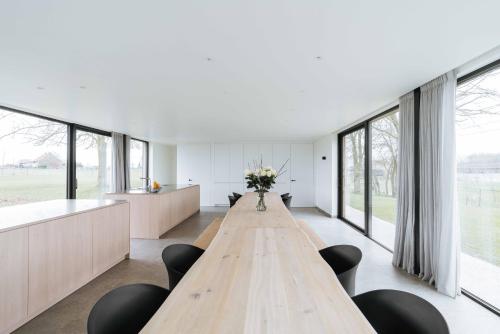 a long wooden table in a room with windows at Woodhouse94 in Zonnebeke