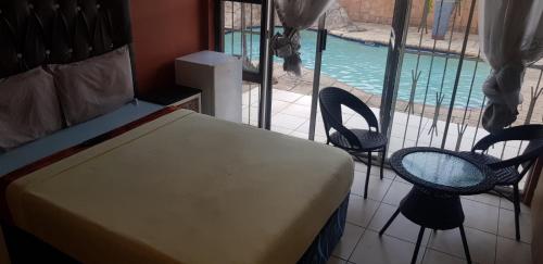 a bedroom with a bed and two chairs and a swimming pool at FK Guest Inn in Alberton