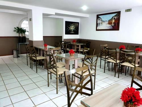 a restaurant with tables and chairs with red flowers at One Hotel in João Pessoa