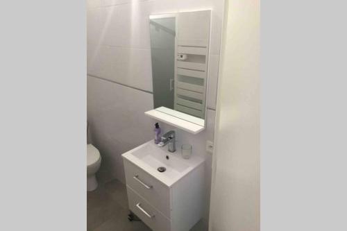 a white bathroom with a sink and a mirror at T3 vue exceptionnelle avec accès privé à la plage, wifi, clim - dansnotreappart-com - in Valras-Plage