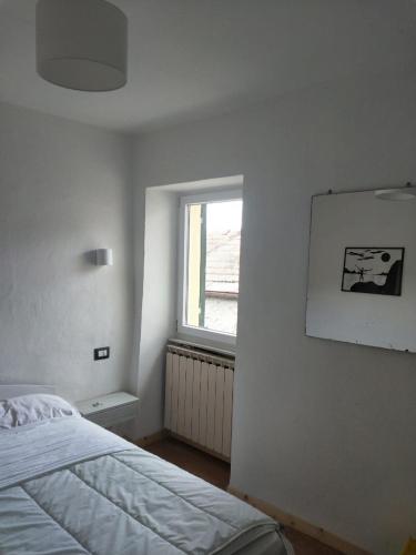 a white bedroom with a bed and a window at IL NIDO VERDE in Groppo