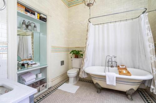 a bathroom with a tub and a toilet and a sink at Burke Mansion in Macon