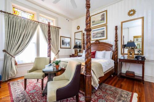 um quarto com uma cama de dossel, uma mesa e cadeiras em Burke Mansion em Macon