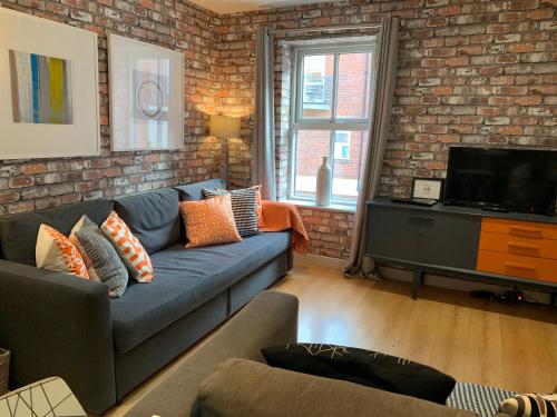 a living room with a blue couch and a brick wall at Russet Quarter, Parking subject to availability in York
