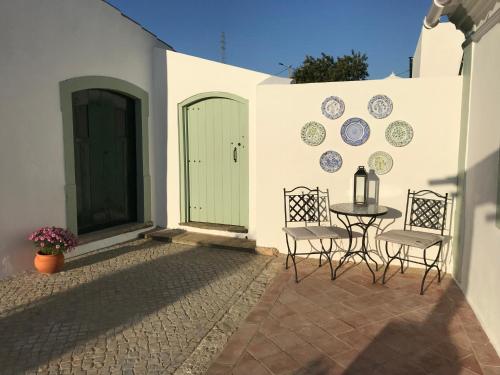 a patio with a table and chairs and a wall at Studio Colina in Tavira