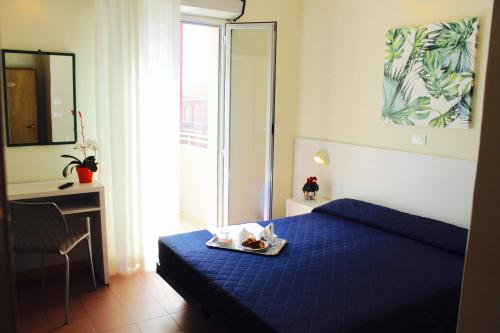 a bedroom with a blue bed with a tray of food on it at Hotel Fedora Rimini in Rimini
