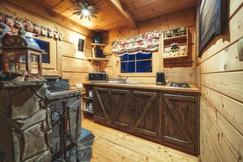 a kitchen with wooden cabinets and a stove in a cabin at Leśna Bacówka in Nowy Targ