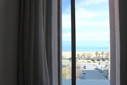 a room with a window with a view of the beach at Hotel Fedora Rimini in Rimini