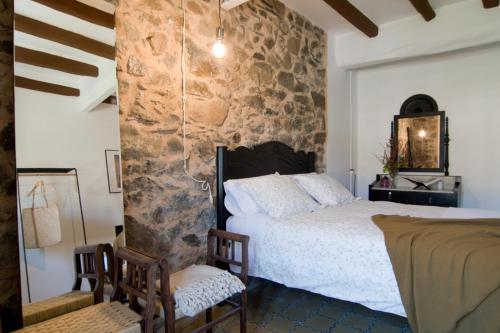 um quarto com uma cama e uma parede de pedra em L'Hostatgeria del Celler em Porrera