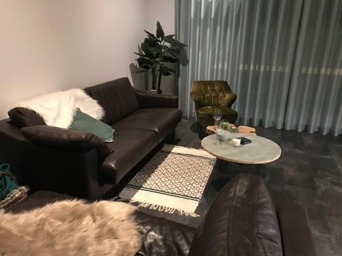 a living room with a leather couch and a table at Natuurhuisje Pine & Oak 6 persoons in Hardenberg