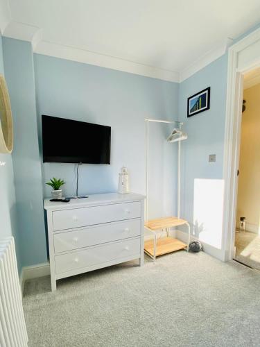 a living room with a tv on a blue wall at Nickleby Nook By the Sea - Meters to the Beach! in Broadstairs