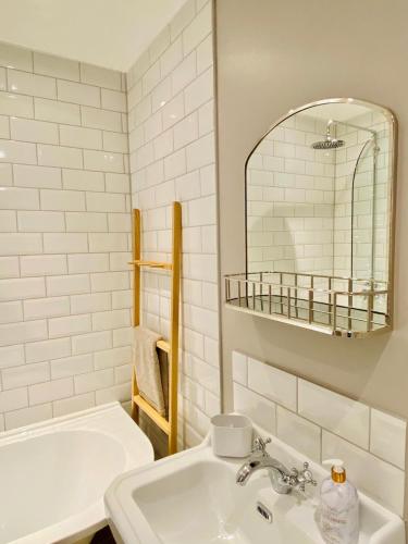 a white bathroom with a sink and a mirror at Nickleby Nook By the Sea - Meters to the Beach! in Broadstairs
