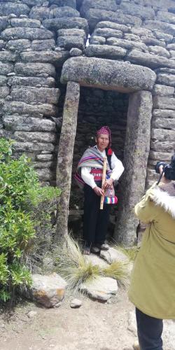 a woman standing in front of a stone wall at Taquile Hospedaje Mario in Huillanopampa