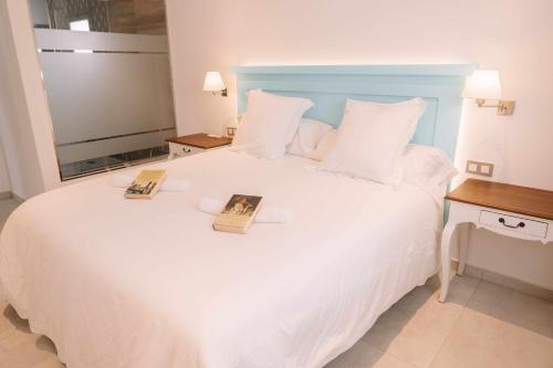 ein Schlafzimmer mit einem weißen Bett mit zwei Büchern darauf in der Unterkunft Villa privada de lujo con piscina, Sabi Sabi in Corralejo