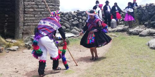 two people in costumes walking down a dirt road at Taquile Hospedaje Mario in Huillanopampa