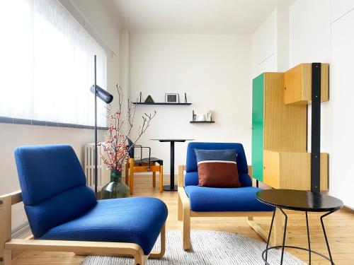 a living room with two blue chairs and a table at B&B Expo House in Antwerp
