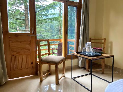 Habitación con 2 sillas, mesa y ventana en Getaway Stays Manali, en Manali