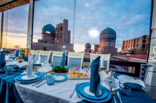 - une table avec des assiettes de nourriture et une vue sur la ville dans l'établissement Bibikhanum Hotel, à Samarcande
