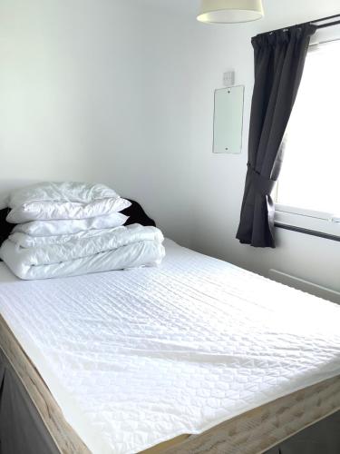 a bed with white sheets and a window at 125 Sundowner in Hemsby