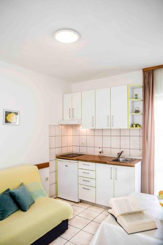 a kitchen with white cabinets and a yellow couch at Apartment Zora in Vodice