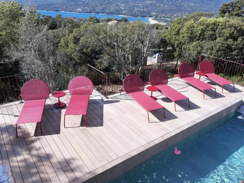 a group of pink chairs sitting on a deck next to a pool at U Castellu, l' hôtel particulier in Propriano