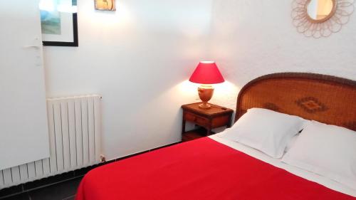 1 dormitorio con cama roja y lámpara roja en una mesa en Entre Terre & Mer, en Ciboure