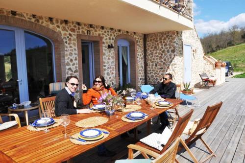 a group of people sitting around a wooden table at montecristo country house in Marsiliana