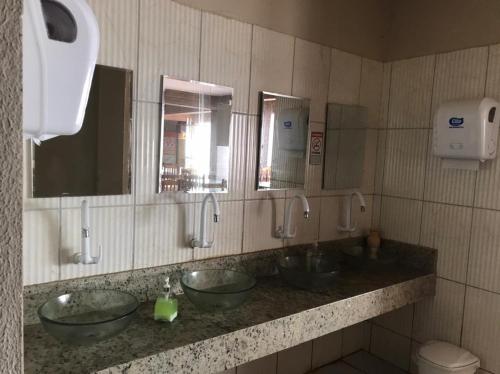 a public bathroom with three sinks and mirrors at Pousada Galeão Pirata in Abrantes