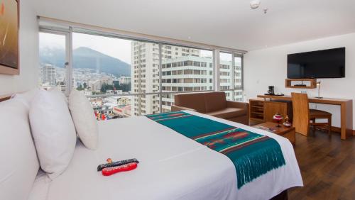 een slaapkamer met een wit bed en een groot raam bij ZEN Hotel in Quito