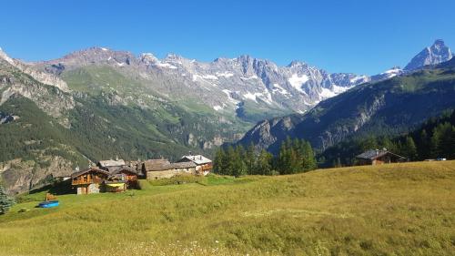a group of houses on a hill with mountains in the background at Le Rascard in Valtournenche