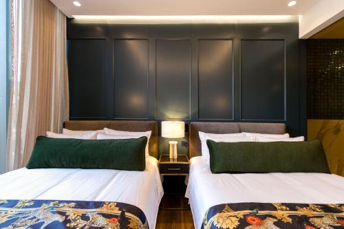two beds with green pillows in a hotel room at Hotel Marquee Medellín in Medellín