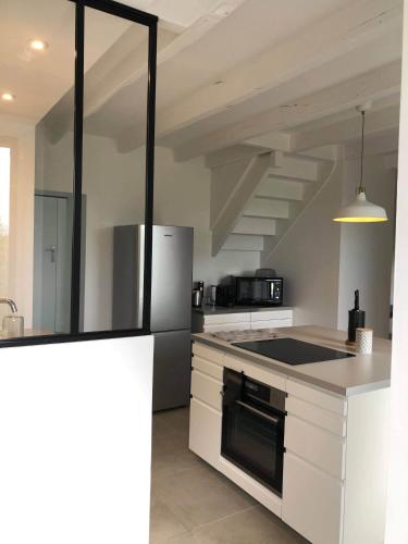 a kitchen with white cabinets and a stove top oven at Maison 2 Ch - 7 Pers - au coeur du Château de Bothané in Guidel
