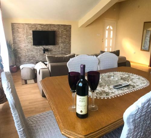 Jovana -- porodicni apartmani Igalo في هرسك نوفي: غرفة معيشة مع طاولة مع كأسين من النبيذ