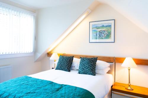 een slaapkamer met een bed met blauwe en witte kussens bij The Albatross in Panbride