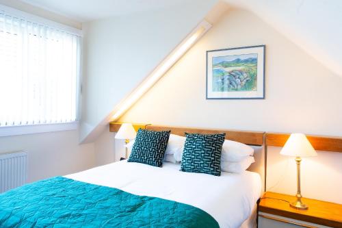 a bedroom with a bed with blue and white pillows at The Albatross in Panbride