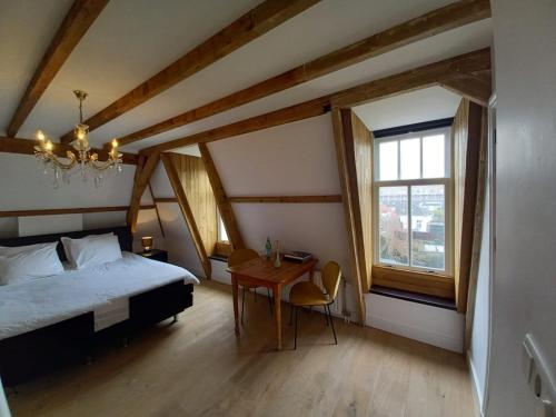 a bedroom with a bed and a table and a window at B&B Van Amsterdam in Middelburg