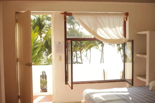 a bedroom with a bed and a window with a view at La Coral Beach House in Puerto Escondido